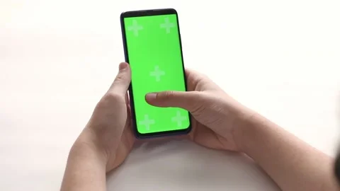 On a light background, a hand is typing in a phone with a green screen Stock Footage 193968848