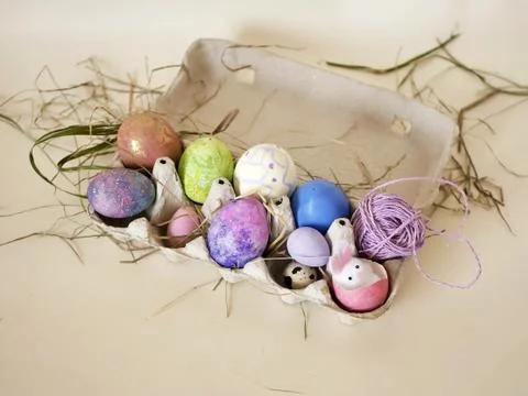 On a light background hay, painted eggs, Easter decor in a tray Stock Photos