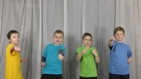 On a light background in multi-colored T-shirts, little athletes do punches Stock Footage 148616901