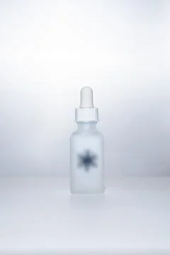 Light backlit face serum in matte bottle with snowflake Stock Photos