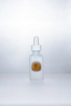 Light backlit face serum in matte bottle with orange Stock Photos