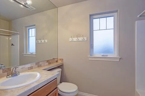 Light bathroom interior with view of vanity cabinet, toilet and small window. Foto stock
