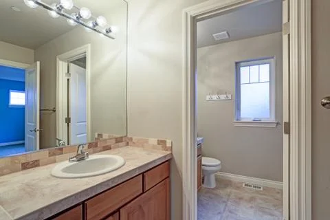 Light bathroom interior with view of vanity cabinet, toilet and small window. Foto stock