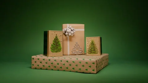 Light beam sliding by green background stack of gift boxes with Christmas trees Stock Footage 254836105