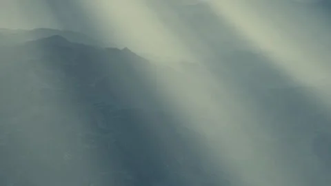 Light beams shine through clouds over a mountain range during a sunny day Stock Footage 340987825