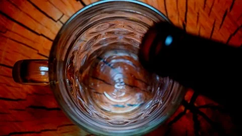 Light Beer is pouring into a big glass on wooden background Stock Footage