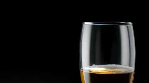 Light beer pouring in glass. With bubbles and foam. Black background. Stock Footage 136384613