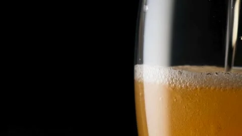 Light beer pouring in glass. With bubbles and foam. Close up. Black background. Stock Footage 136385166