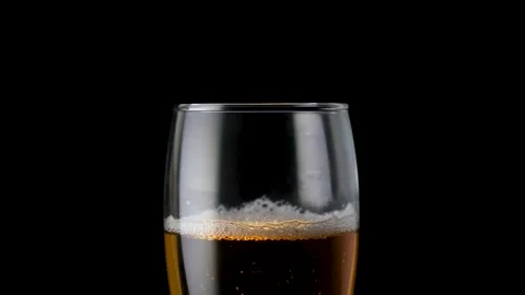 Light beer pouring in glass. With bubbles and foam. Black background. Stock Footage 136385233