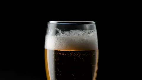 Light beer pouring in glass. With bubbles and foam. In the center of the frame Stock Footage 136389770