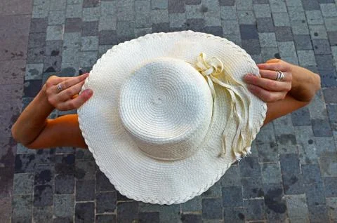 Light beige beach hat in the hands of a young woman. Selective focus Stock Photos