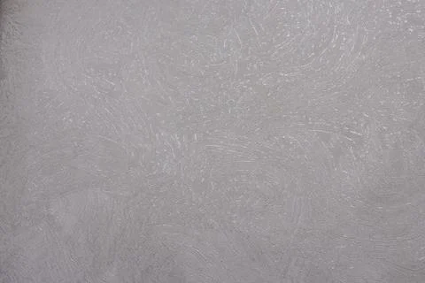 Light beige stucco wall with subtle swirling plaster texture, providing a soft Stock Photos