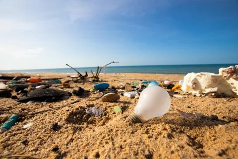 Light blub, glass bottles and garbage waste on the beach Stock Photos