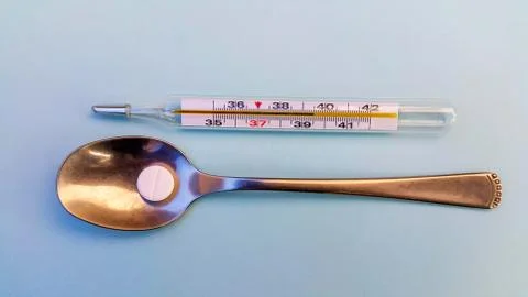 On a light blue background, a thermometer showing a high temperature Stock Photos