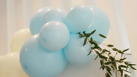 Light blue celebration balloons with greenery detail in soft ambient light Stock Footage 310651463