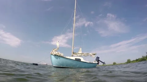 Light blue cute small sail boat floating around for anchor Stock Footage 52177367