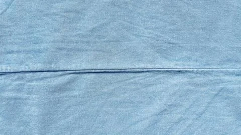 Light blue denim fabric texture with horizontal seam showing natural weave pa Stock Photos