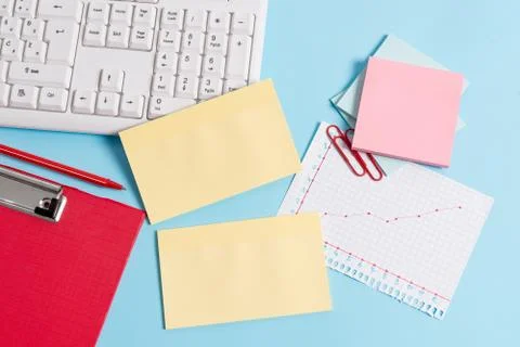 Light blue desk with different sizes of empty paper notes, computer keyboard and Stock Photos