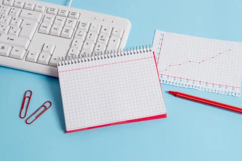 Light blue desk with empty paper notes, computer keyboard and office appliances 写真素材