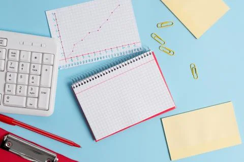 Light blue desk with empty paper notes, computer keyboard and office appliances Stock Photos