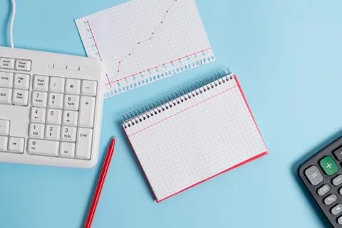 Light blue desk with empty paper notes, computer keyboard and office appliances Stock Photos