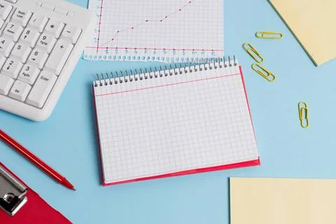 Light blue desk with empty paper notes, computer keyboard and office appli... Stock Photos