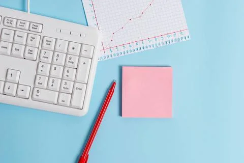Light blue desk with empty paper notes, computer keyboard and office appli... Stock Photos