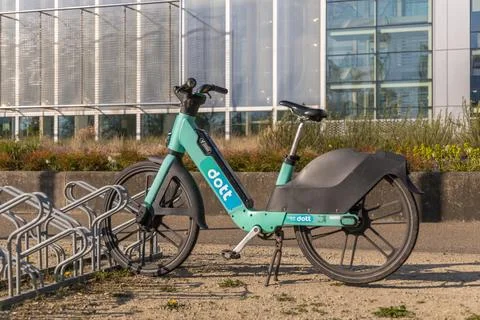 A light blue Dott rental e-bike is parked in a rack on a sunny day in Utrecht 스톡 사진