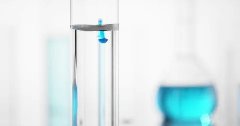 Light Blue liquid is dropped into test tube filled with water Stock Footage 74853249