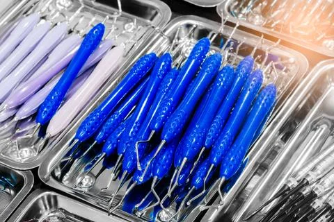 Light blue plastic baskets hold shiny metal surgical instruments. Tools inclu Stock Photos