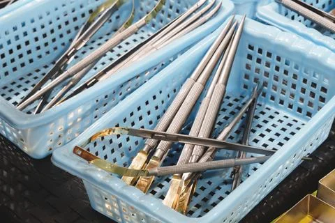Light blue plastic baskets hold shiny metal surgical instruments. Tools inclu Stock Photos