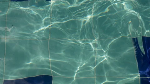 A Light Blue Pool with Sunlight Reflections and Water Ripples in Slow Motion Видео 303736287