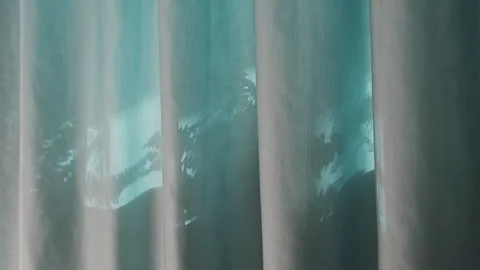 Light blue sheer curtain moving gently in the wind. Sunlight streams Stock Footage 346539366