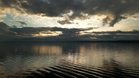 Light breaking through the clouds at sunrise over the water  Stock Footage 294706971