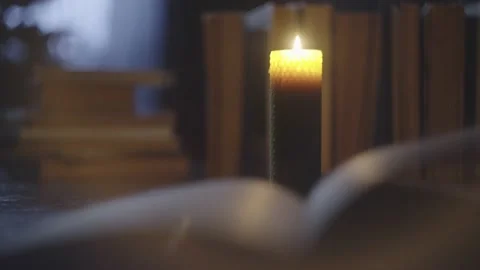 A light breeze moves the pages of the book against the background of the candle. Stock Footage 234919973