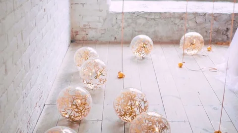 Light bright balloons lie and roll on floor, filled with golden serpentine Stock Footage 100193839