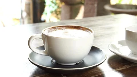 A light brown fresh mocha with a pretty latte art outdoors on a cafe in Paris. 動画素材 334648789