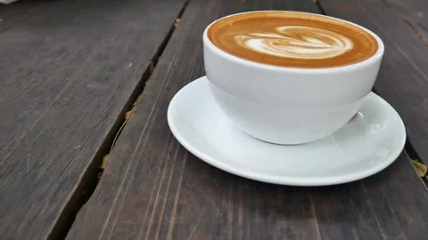 A light brown fresh mocha with a pretty latte art outdoors on a cafe in Paris. 動画素材 334650816