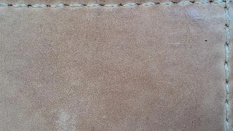 Light brown suede leather surface featuring detailed white thread stitching Stock Photos