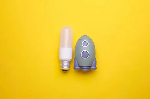 Light bulb and small rocket toy on yellow background 写真素材