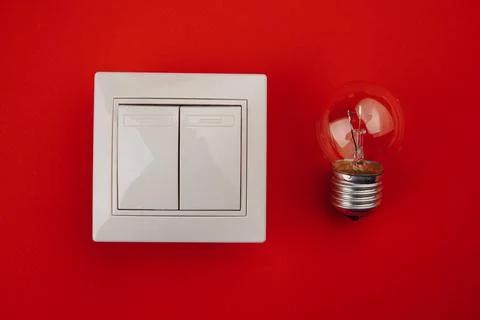 Light bulb and switch on red background Stock Photos