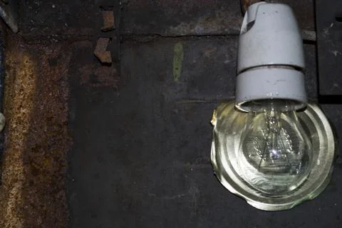 Light bulb on the background of old rusty iron, reflector cover from the can. Stock Photos