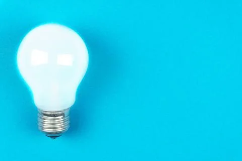 A light bulb on a blue background on the left. Top view Stock Photos