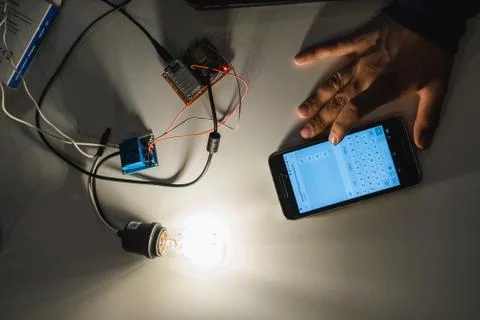 Light bulb connected to a circuit board with smartphone Stock Photos