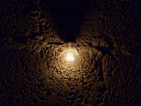 Light bulb on a dark rough stone background. Gloomy dark background. Foto stock