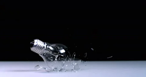 A light bulb falls and breaks against a black background, flying debris Video stock 161923661