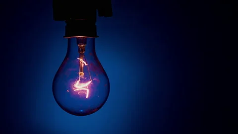 Light Bulb Flashes on a Blue Background in the Dark Video stock 234518918
