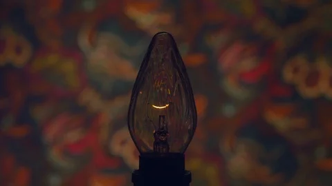 Light bulb glowing against decorative wall Stock Footage 103784503