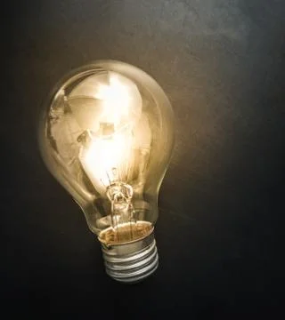 Light bulb glowing on black background Stock Photos