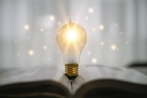 Light bulb glowing on book, idea of ??inspiration from reading, innovation .. Stock Photos
